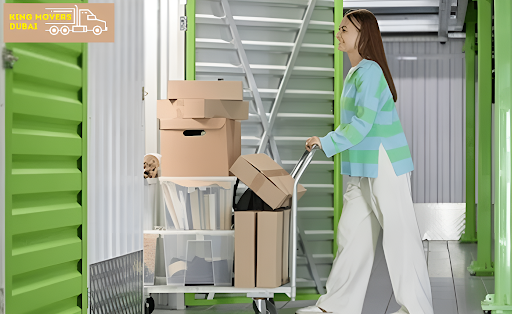 A woman pushing a cart filled with boxes inside a storage unit labeled Cheap Storage and Moving.