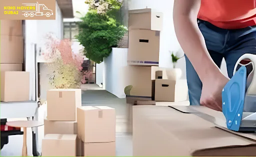 A man uses a box cutter to slice through cardboard, showcasing Dubai packing and moving services in action.