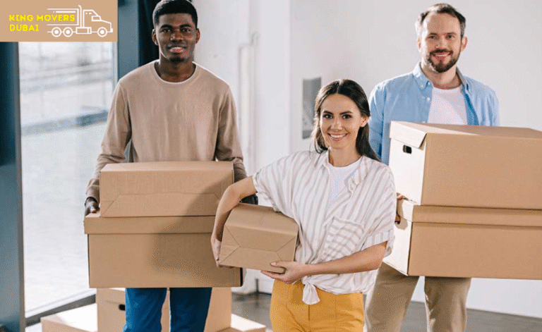 Three movers carrying boxes in a studio apartment movers in Dubai, preparing for relocation.