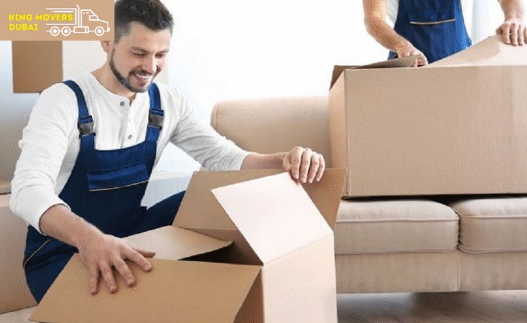 Two men in overalls lifting boxes and adjusting a couch as they assist with an apartment moving in Dubai.