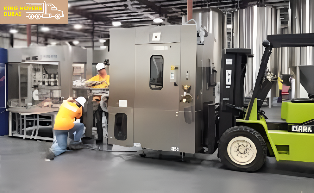 A forklift operates in a factory while workers oversee the industrial machinery relocation process.