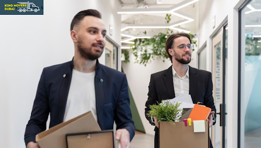 Two men carrying boxes in an office hallway during a corporate international move.