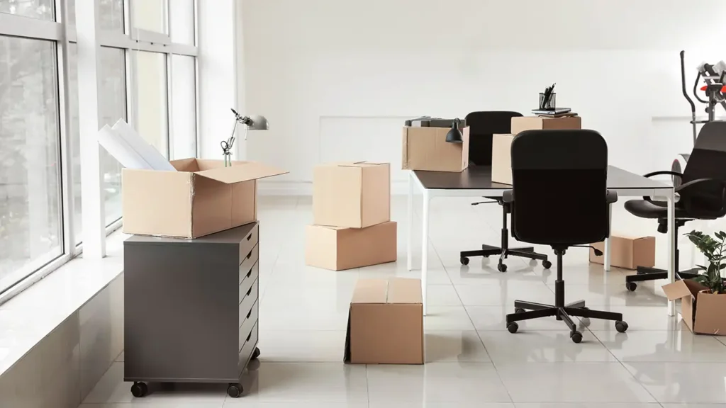 Staff members carrying boxes in an office setting during a corporate move.